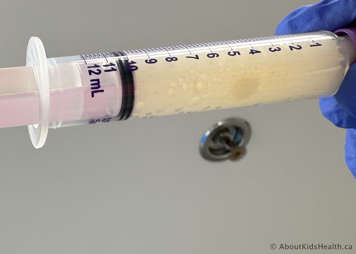 Oral syringe with partially disintegrated tablet in liquid with some bubbles