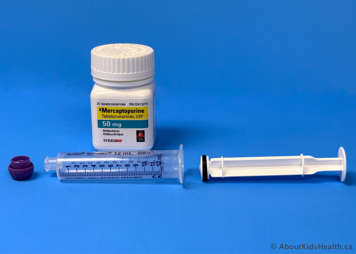 Bottle of mercaptopurine tablets behind an oral syringe with the plunger pulled out