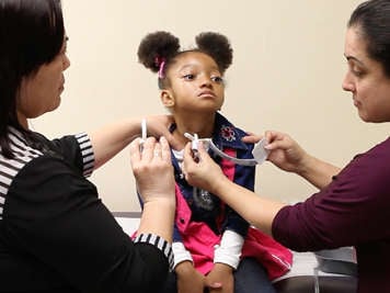 Two people removing a child’s tracheostomy tube