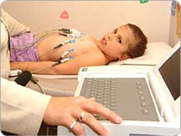 child lying down for electrocardiogram with electrodes on arms and chest