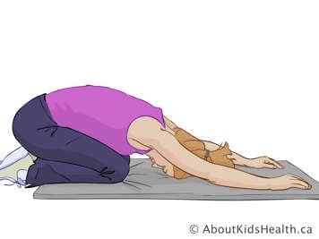 Woman sitting on her heels on a mat, with head resting on the mat and arms stretched out in front of her