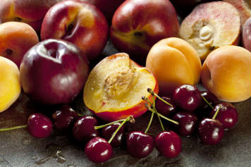 Various fruits with some fruit cut in half to show the pit