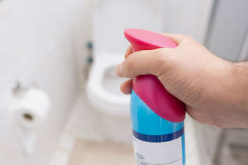 hand spraying air freshener bottle