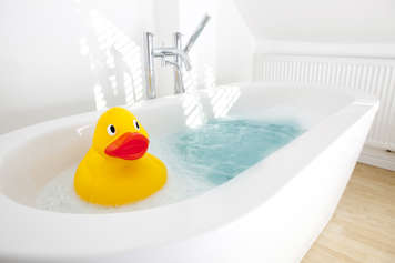 Bath tub filled with water and a rubber duck