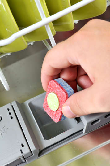 Person putting a dishwasher tab into the dishwasher