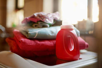 Jug of laundry detergent next to folded laundry