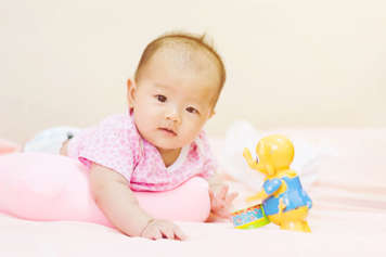 Baby showing tummy time with a roll under their chest