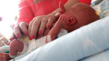 A woman gently resting her hands on an infant's middle