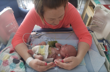 A woman with her arms encircling her baby's body