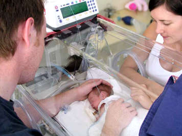 Parents regardant leur bébé dans un incubateur