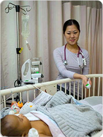 A nurse using a machine with a hand-held button to give a patient pain medicine.