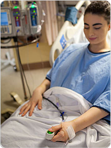 A patient using a machine with a hand-held button to receive pain medicine.