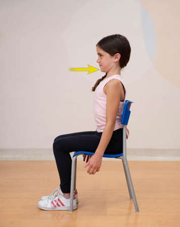 side view of girl sitting in chair tucking her chin