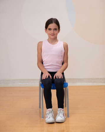 girl sitting in chair with back straight and hands on knees