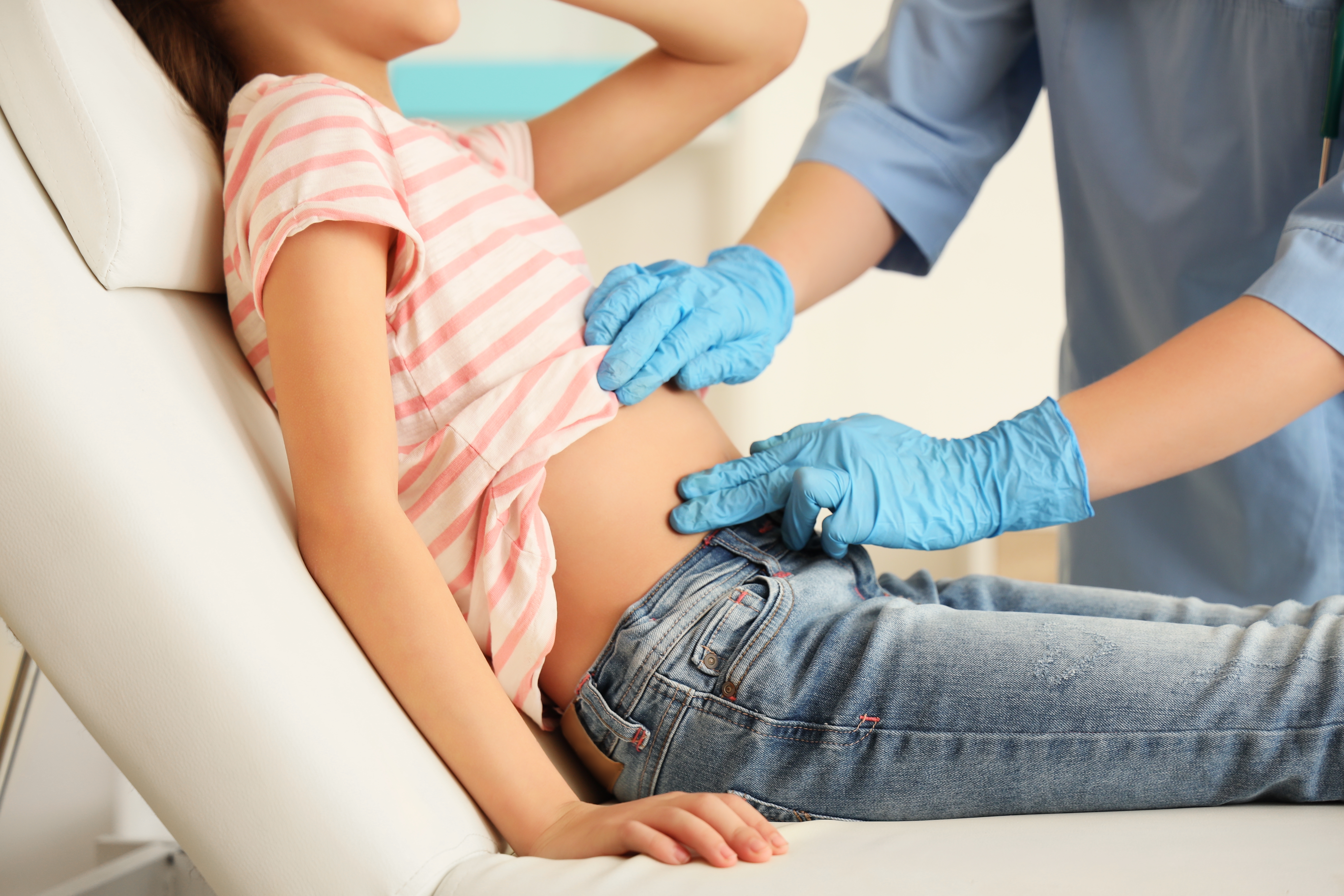 Health-care provider pressing on a child's lower-right abdomen 
