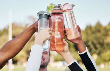 Children's arms raised to hold their reusable bottles together in the air