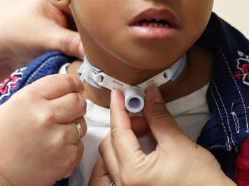 Main person removing the Velcro strap from the tracheostomy tube