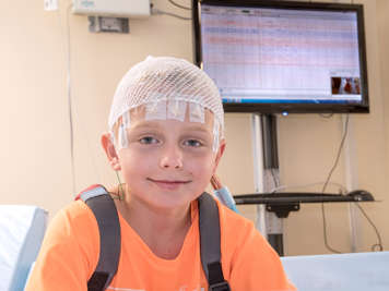 Child with electrodes attached to head for an EMU session