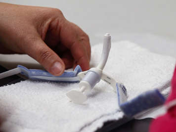 Placing the tracheostomy tube upright to keep it clean