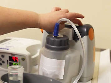 Person pressing the on and off switch on a suction machine.