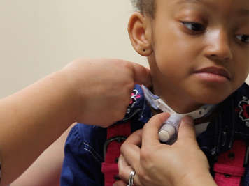 Checking tracheostomy tube tie fit with finger.