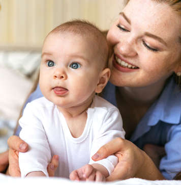 Mother with baby rocking them on extended arms