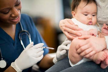 Parent holding infant in upright position before needle poke
