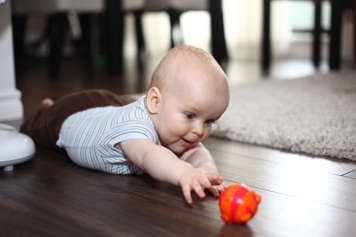 Baby on their tummy reaching for a toy